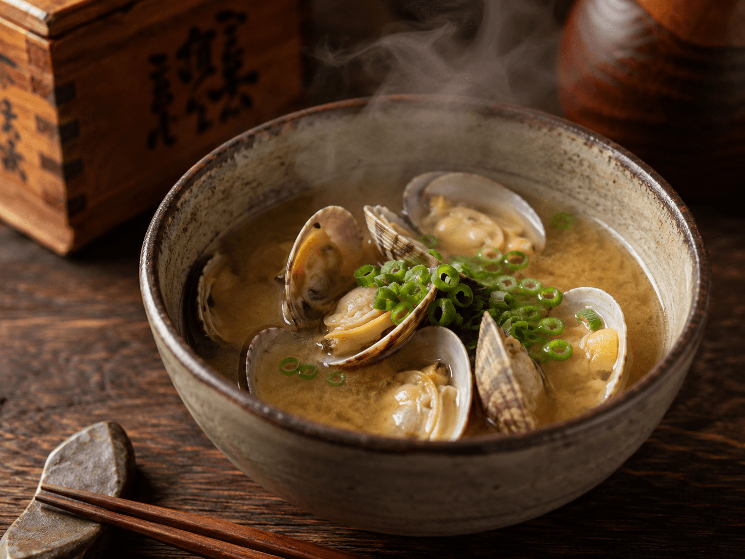 あさりの口が開いたお味噌汁のクローズアップ。湯気が立ち上り、ネギが添えられた和風の一杯