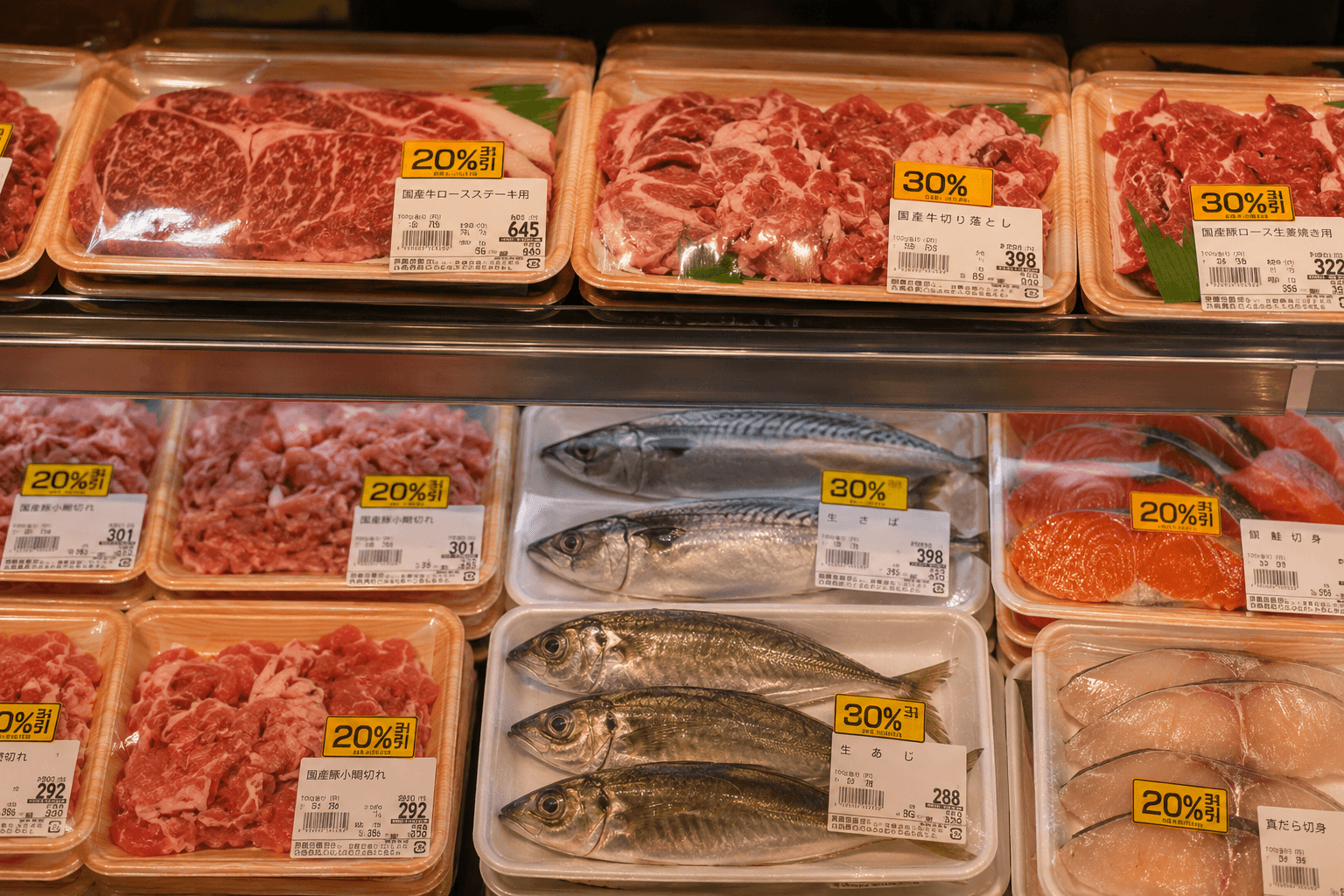 スーパーの精肉・鮮魚コーナー。黄色い値引きシールが貼られた肉や魚のパックが並ぶ夕方の売り場